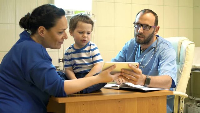 Doctor with tablet talking to mother with child about test results in office
