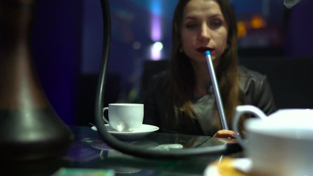 Beautiful young woman smoking a hookah and drinking tea