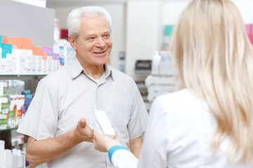 Obraz premium Young female pharmacist helping an elderly customer