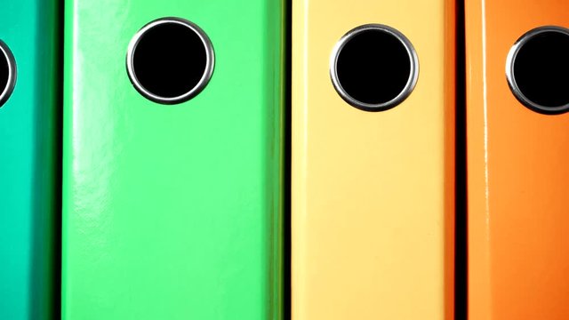 Close up of many colorful file folders, ring binders as vivid color office background. Dolly slider shot 4K ProRes HQ codec