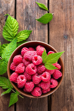 Fresh raspberry with leaves on wooden background