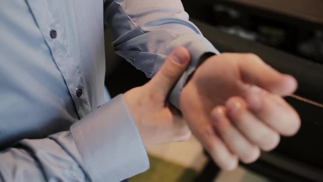 Close-up view of male hands buttons a shirt. Man clasping cuffs on a shirt. Businessman getting ready for a job.