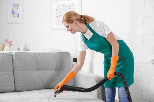 Woman cleaning couch with vacuum cleaner