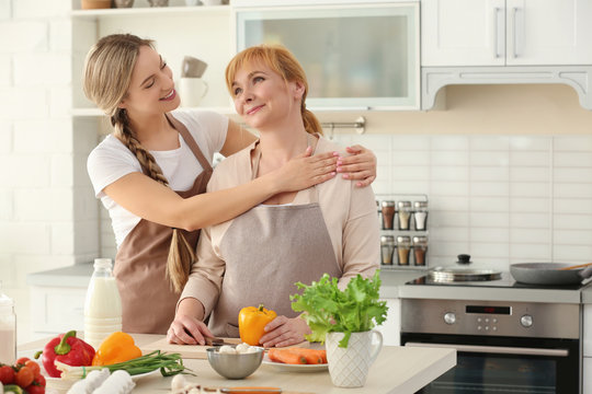 Young woman and her mother cooking in kitchen