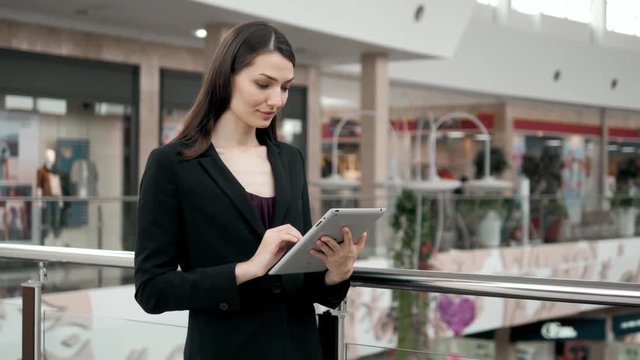 Smiling mature professional businesswoman in office. Holding a digital tablet . Woman brunette in airport or shopping mall
