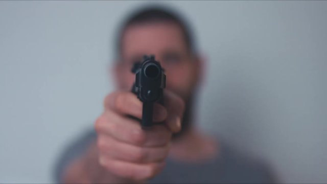Thug pointing a gun into a camera. 4K UHD RAW edited footage