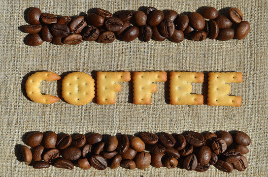 Fototapeta Coffee. The word from the edible letters lies on the gray canvas with coffee beans