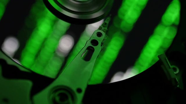 Close-up shot of interior of computer hard drive with matrix style code in the reflection.