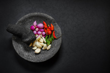 Traditional stone motar & pestle from Asia with spicy ingredients. - obrazy, fototapety, plakaty