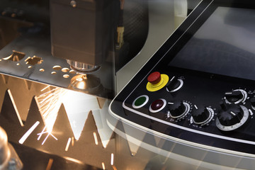 The CNC laser cut machine while cutting the sheet metal with the sparking light and the control panel .The hi-precision sheet cutting process by laser cut
