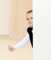 boy peeks out from behind the banner