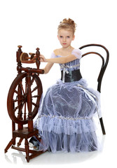Little girl sitting at a spinning wheel.