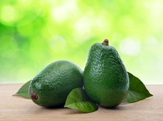 Avocado with leaf on a wooden board.