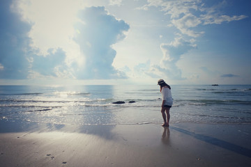 Happy woman relaxation on the sunny sea beach under sunlight sky with clouds at summer day, travel vacation, landscape beach background