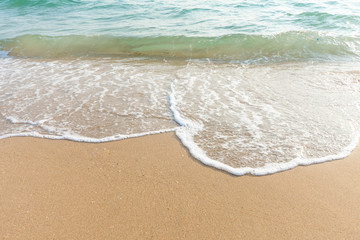Soft wave of blue ocean on sandy beach at sunny day. Background subject is soft focus