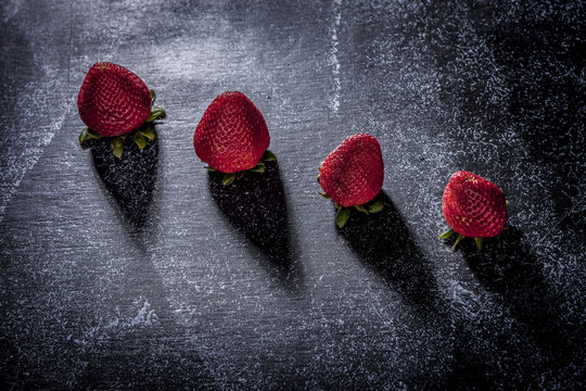 Four strawberries and their shadows.