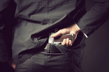 Gun concealed, A man, policeman or gangster concealing his gun behind his back.