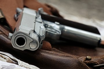 Obraz premium Semi-automatic handgun lying over a Leather handbag, .45 pistol, Close-up Barrel.