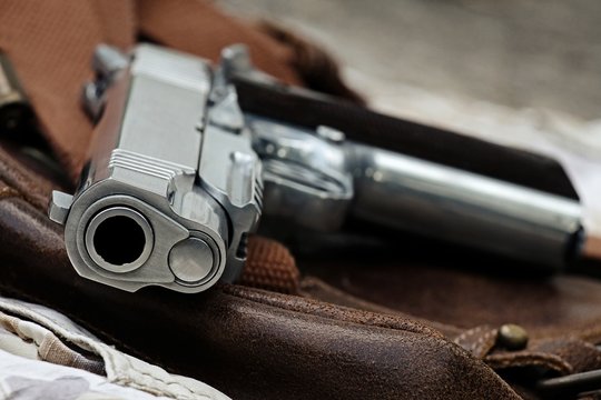 Semi-automatic handgun lying over a Leather handbag, .45 pistol, Close-up Barrel.