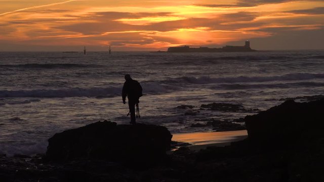 Silhouette of photographer at sunset taking photos at beach