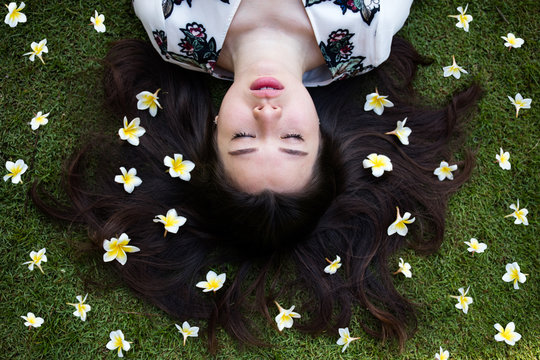 Asian Beautiful Young Woman Lying On Lawn With Flowers