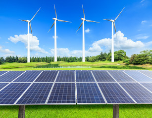Wind turbines and solar panels on green field