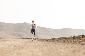 Fit Lady Jogging on Dirt Road with Mountains in Background