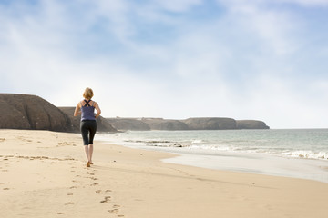 Woman Running Barefoot on the Beach Leaving Footprint Trail
