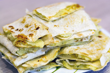 Wheat tortillas on grill, with potatoes and onions, snack, tasty flat bread for picnic
