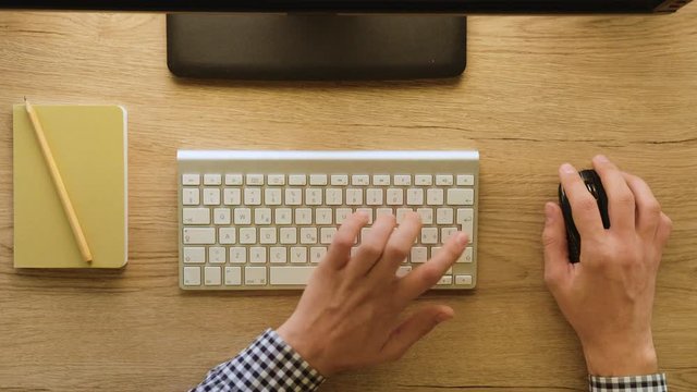 Male hands typing on keyboard on wooden table background. Top view. Office desk