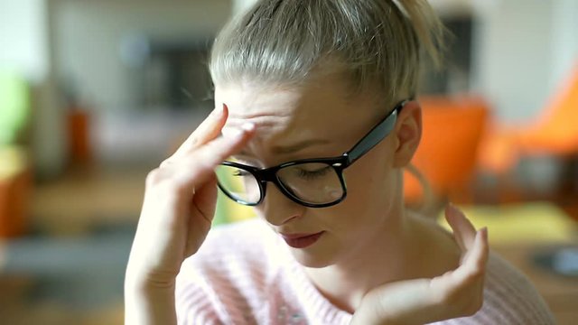 Pretty girl takes off glasses because of painful migraine
