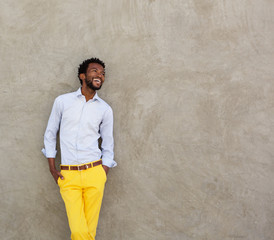confident african american man leaning on wall laughing