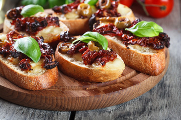 Appetizer bruschetta with sun-dried tomatoes, olives and mozarella.