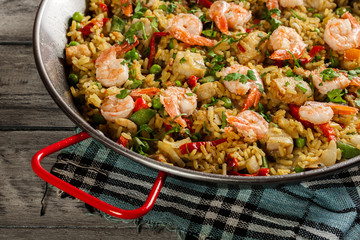 Traditional seafood paella with shrimp, fish and chicken seved in paellera