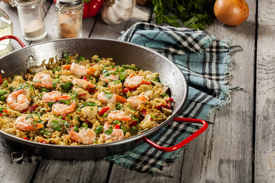 Traditional seafood paella with shrimp, fish and chicken seved in paellera