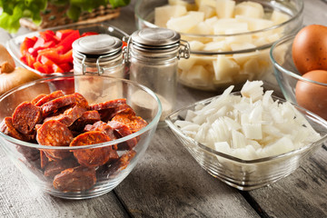 Tortilla de patatas. Ingredients for preparing spanish omelette with sausage chorizo, potatoes, paprika and egg
