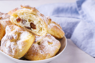 Homemade hungarian Cheese Puff Pastry Parcels. Cottage cheese puffs (buns, patties, cheesecakes) with raisins on light grey concrete background. Selective focus 