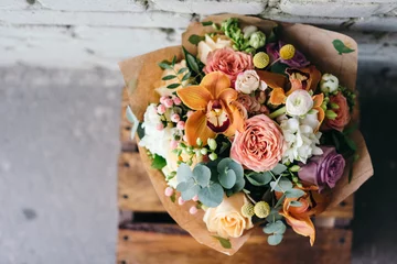 Fototapete Colorful  bouquet of different fresh flowers against brick wall. Bunch of orchids, roses, freesia and eucalyptus leaves. Rustic flower background © pidphoto