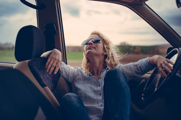 Young woman in car. Enjoy road trip. Relaxing in car.