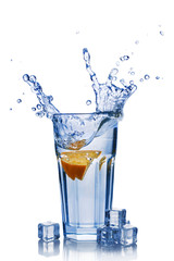 Splash in glass of blue water with orange slice and ice cube