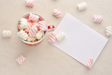 A blank sheet of paper, a glass of hot chocolate with marshmallows on a light background.