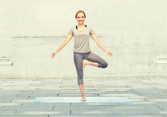 woman making yoga in tree pose on mat