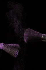 Make up brush with purple dust on black background