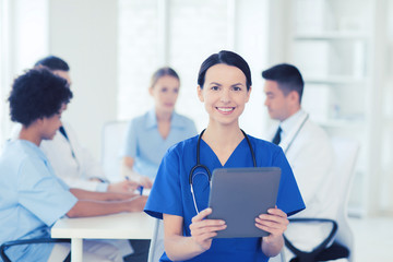 Fototapeta premium happy doctor with tablet pc over team at clinic