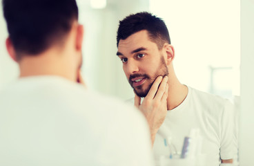 happy young man looking to mirror at home bathroom