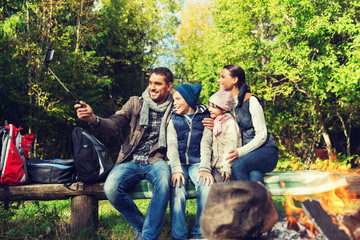 Naklejka na ściany i meble family with smartphone taking selfie near campfire