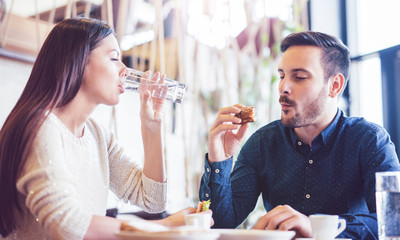 Beautiful young couple sitting in a cafe, having breakfast. Love, food, lifestyle