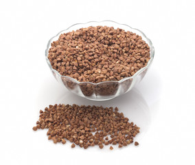 Buckwheat grain and transparent saucer isolated on white background