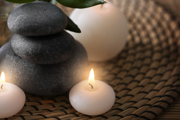 Obraz na płótnie Canvas Spa stones with candles on wicker mat