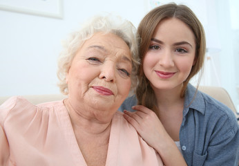 Beautiful girl with grandmother taking selfie on couch at home